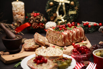 Traditional French terrine covered with bacon on dark wooden background with Christmas decorations