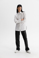 Studio photoshoot of a young brunette woman wearing casual clothing against a white background.  Natural makeup and hairstyle