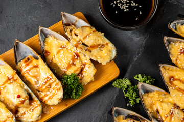 Appetizing mussels baked with cheese and poured with sauce. View from above. Close-up.