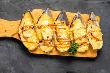 Mussels in shell with cheese and teriyaki sauce, with sesame seeds, top view.