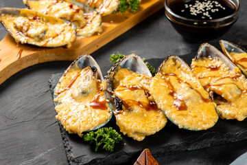 Baked mussels topping with garlic butter sauce and spicy chilli sauce on the side.
