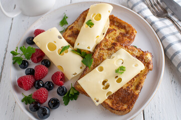 Breakfast sandwich with cheese made with french toast and served with fresh berries