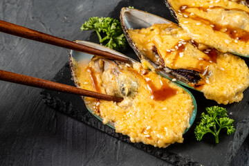 Eating baked mussels under cheese with chopsticks.