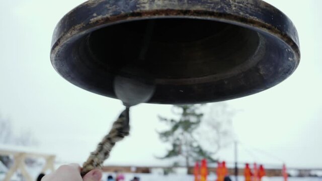 The ringer pulls the rope of a bronze bell.