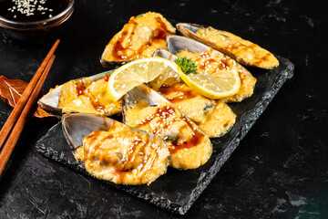 Appetizing appetizer of baked mussels with cheese sauce served on a dark flat stone.