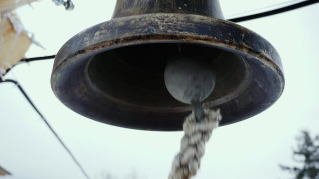 The ringer pulls the rope of a bronze bell.