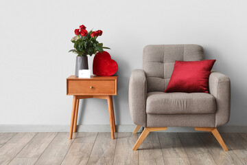 Bouquet of flowers and gift for Valentine's Day on table near armchair in interior of room