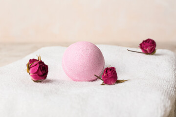 Bath bomb, clean towel and dried rose flowers on table, closeup