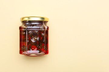 Jar of tasty pine cone jam on beige background