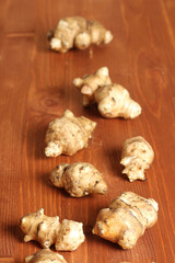 Raw organic Jerusalem artichokes on a wooden background. Healthy food concept. Vertical photo, selective focus