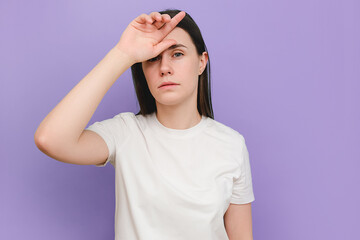 Portrait of unhappy sad young brunette woman suffering from headache, frustrated dizzy flu-sick girl feeling unwell, fever and flue symptoms, stress tension, isolated on purple studio background wall