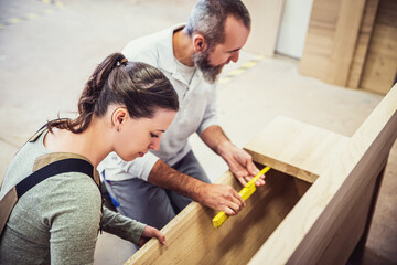 male and female carpenter at work, man and woman are crafting with wood in a workshop - obrazy, fototapety, plakaty