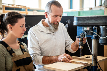 male and female carpenter at work, man and woman are crafting with wood in a workshop