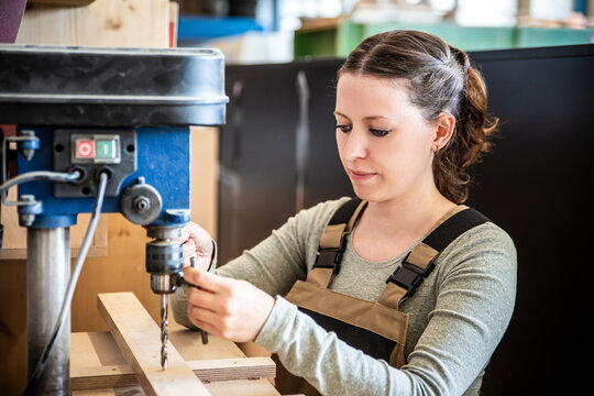female craftman is working with a drill press