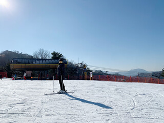 스키장 슬로프 위의 스키복을 입고 서있는 여자 / A woman standing on a ski slope...