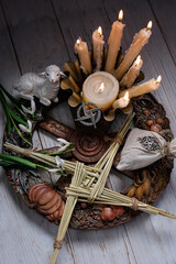 Wiccan altar for Imbolc sabbat. pagan festive ritual. Brigid's cross amulet, candles, wheel of the...