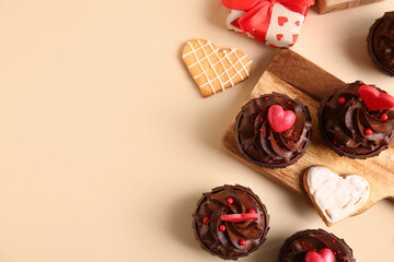 Tasty chocolate cupcakes for Valentine's day and cookies on beige background