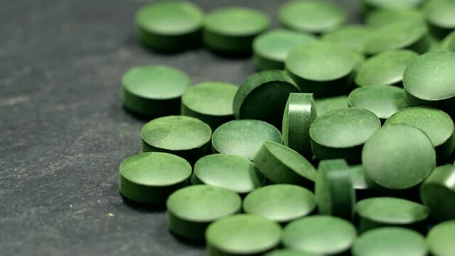 Spirulina (chlorella) green tablets rotation background. Close up