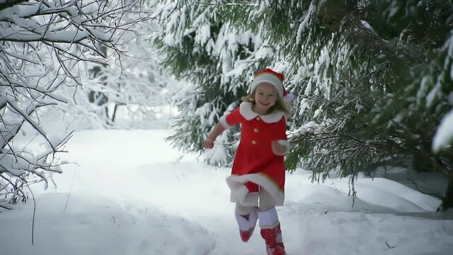 Happy christmas girl smille in santa costume in snow. Winter forest with snowdrifts and snacks. child laughs at new year and walks outside. red suit hat. Dance have fun. Portrait laughing childhood.