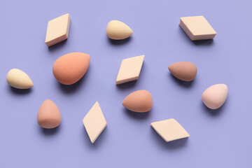 Different makeup sponges on purple background