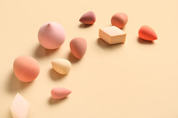 Different makeup sponges on beige background