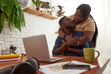 Woman hugging her boyfriend while he working