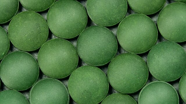 Spirulina (chlorella) green tablets rotation background. Close up