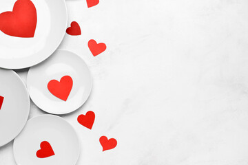 Beautiful plates with paper hearts on white background