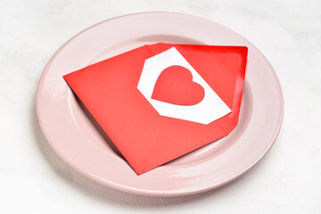 Beautiful plate and envelope with paper heart on white background