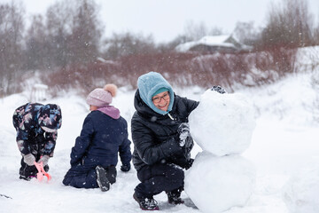 Fototapeta na wymiar Mom and children make a snowman