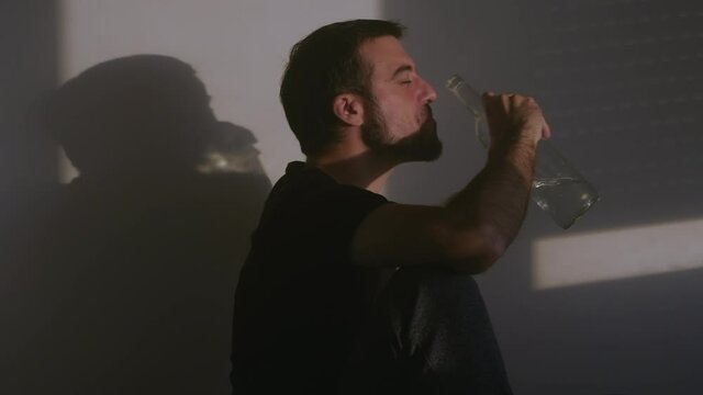 Male alcoholic with bottle of votka drinking at home