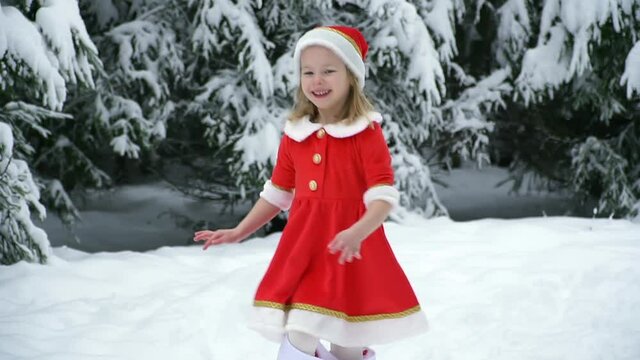Happy christmas girl smille in santa costume in snow. Winter forest with snowdrifts and snacks. child laughs at new year and walks outside. red suit hat. Dance have fun. Portrait laughing childhood.