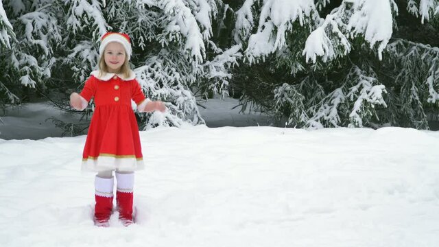 Happy christmas girl smille in santa costume in snow. Winter forest with snowdrifts and snacks. child laughs at new year and walks outside. red suit hat. Dance have fun. Portrait laughing childhood.