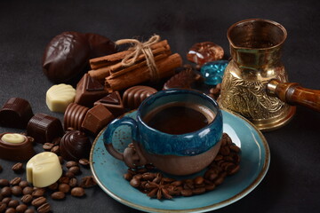 Fototapeta na wymiar Coffee cup, beans, chocolate on old kitchen table Assortment of dark, white and milk chocolate sweets, zefir (zephyr). Spices, cinnamon.