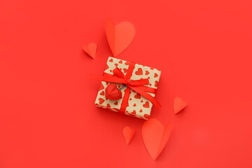 Beautiful gift box and paper hearts on red background. St. Valentine's Day