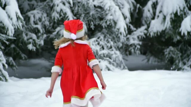 Happy christmas girl smille in santa costume in snow. Winter forest with snowdrifts and snacks. child laughs at new year and walks outside. red suit hat. Dance have fun. Portrait laughing childhood.