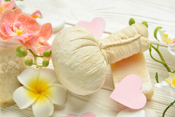 Herbal pouch and flowers for Valentine's Day celebration on light wooden background, closeup