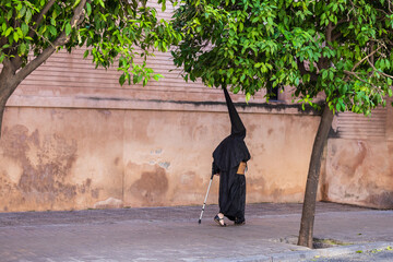 Nazareno caminando con muleta por las calle de Sevilla en la Semana Santa.