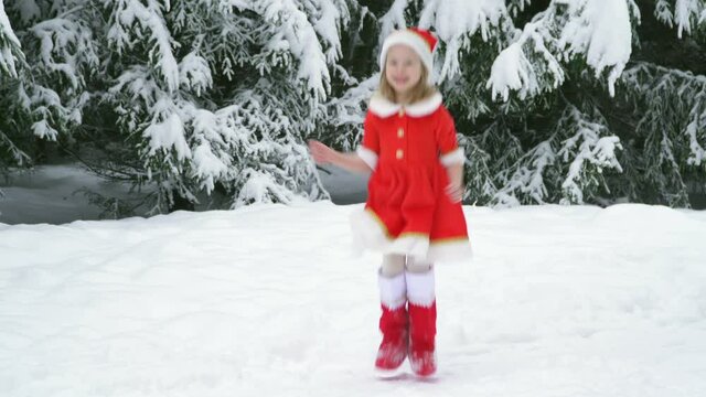 Happy christmas girl smille in santa costume in snow. Winter forest with snowdrifts and snacks. child laughs at new year and walks outside. red suit hat. Dance have fun. Portrait laughing childhood.
