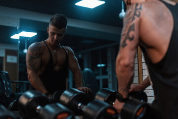 Fototapeta na wymiar Muscular man bodybuilder trains and does a workout in the gym. Sporty lifestyle