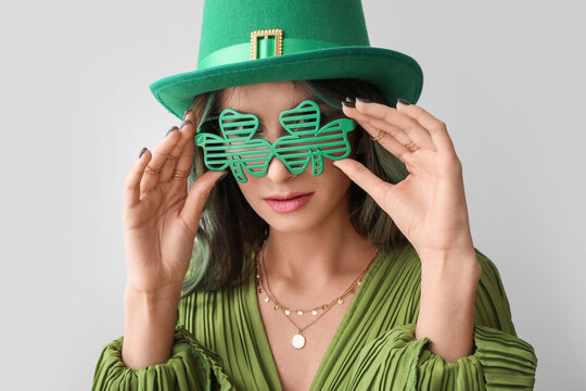 Stylish young woman dressed for St. Patrick's Day party on light background
