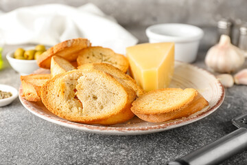 Plate of tasty croutons with cheese on grey background