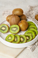 Plate with fresh cut kiwi on light background, closeup