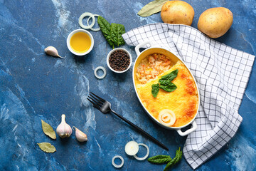 Baking dish with tasty English fish pie and fresh potatoes on blue background