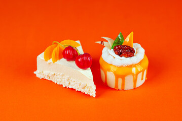 Two pieces of white cake with yellow cream. Cake with fruit on an orange background.