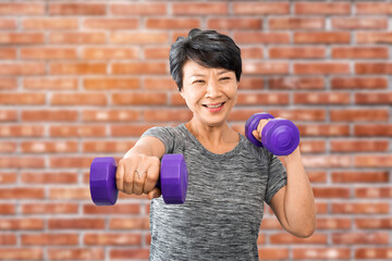 Attractive senior fitness asian woman training, exercising at home with dumbbells isolated on white...