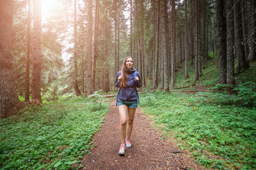 Naklejka na ściany i meble Young smiling woman walking on footpath in the forest.
