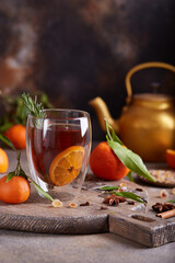 Black tea with orange, rosemary, and spices. Hot healthy winter or autumn beverage.  - obrazy, fototapety, plakaty