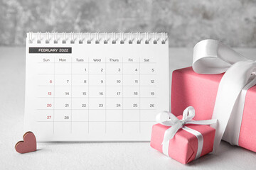 Calendar with gifts on table against grunge background. Valentine's Day celebration
