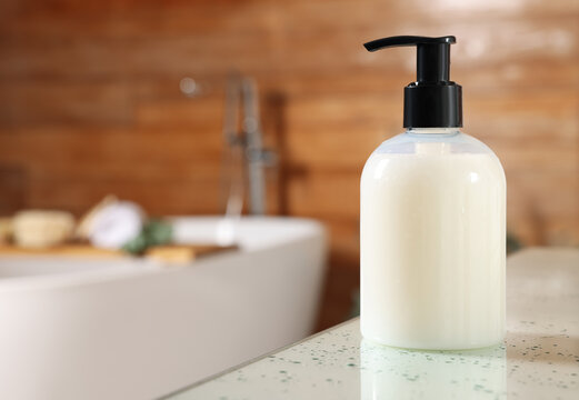 Dispenser of liquid soap on white table in bathroom, space for text